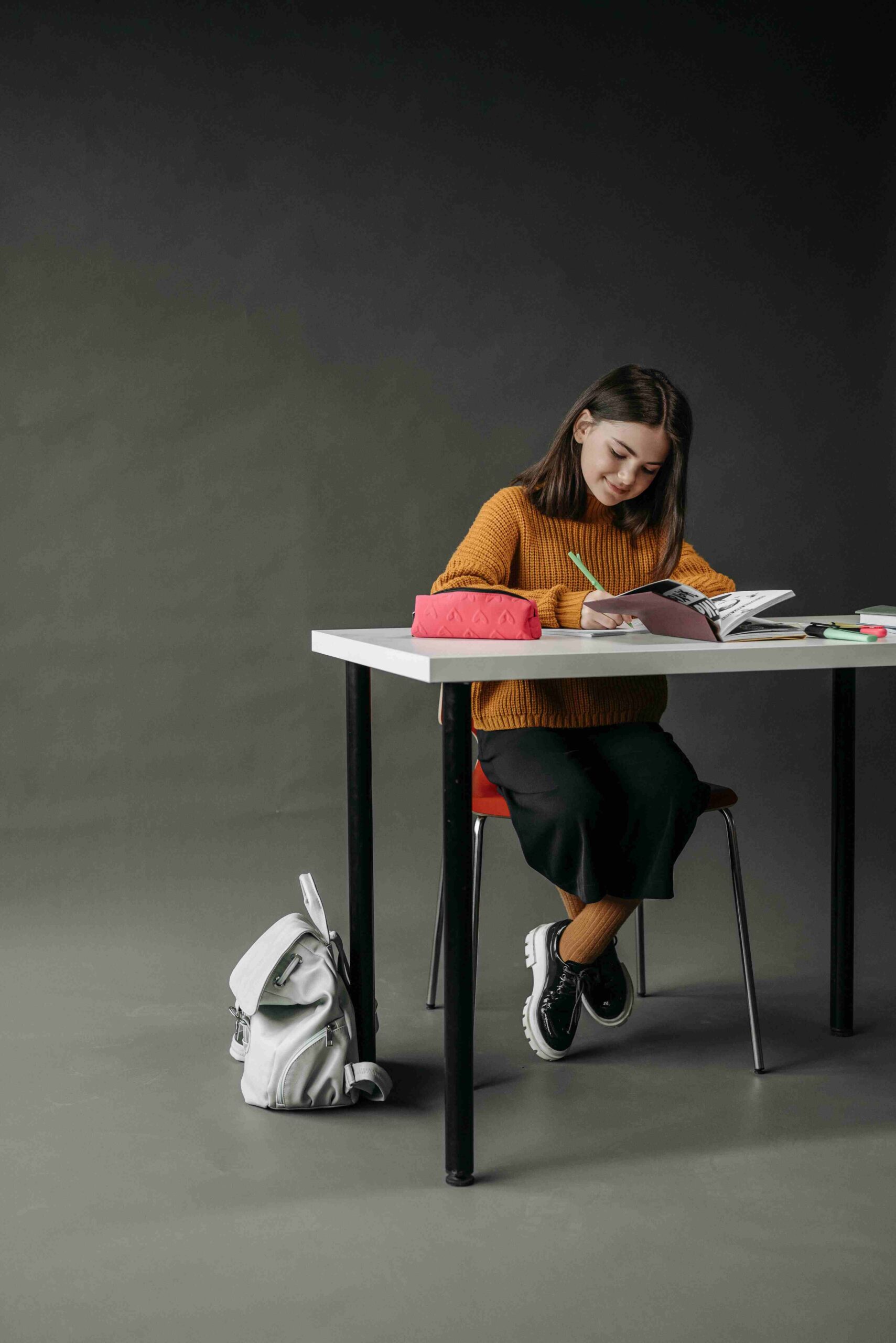 A young girl studying hard with a smile on her face.