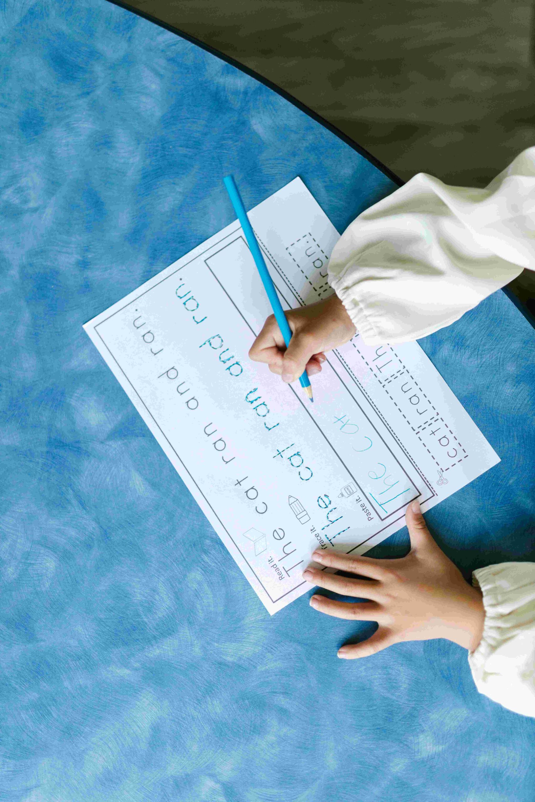 A kid tracing words on a piece of paper.