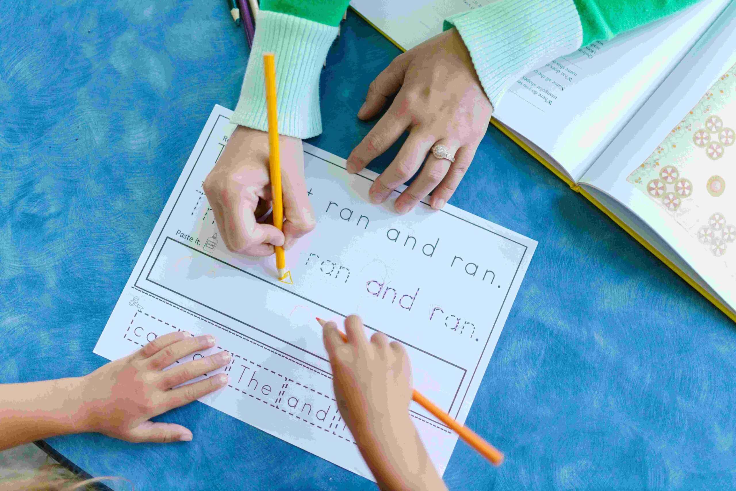 Two kids tracing english sentence with pencils on a piece of paper