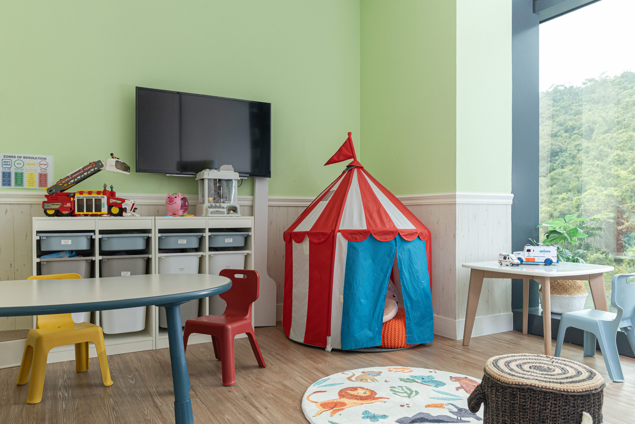 Sprout in Motion ABA behavioural therapy room in Wong Chuk Hang with open glass window with natural lights and TV, tables, baby chairs, carpet and a cute tent